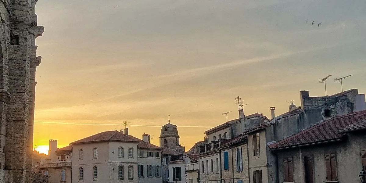 L'amphithéâtre romain d'Arles au soleil couchant, vu depuis la rue qui longe ses arcades.